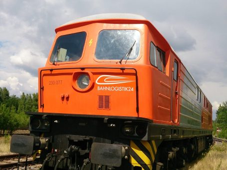 Oranger Diesellokomotive mit einem klaren Himmel im Hintergrund.